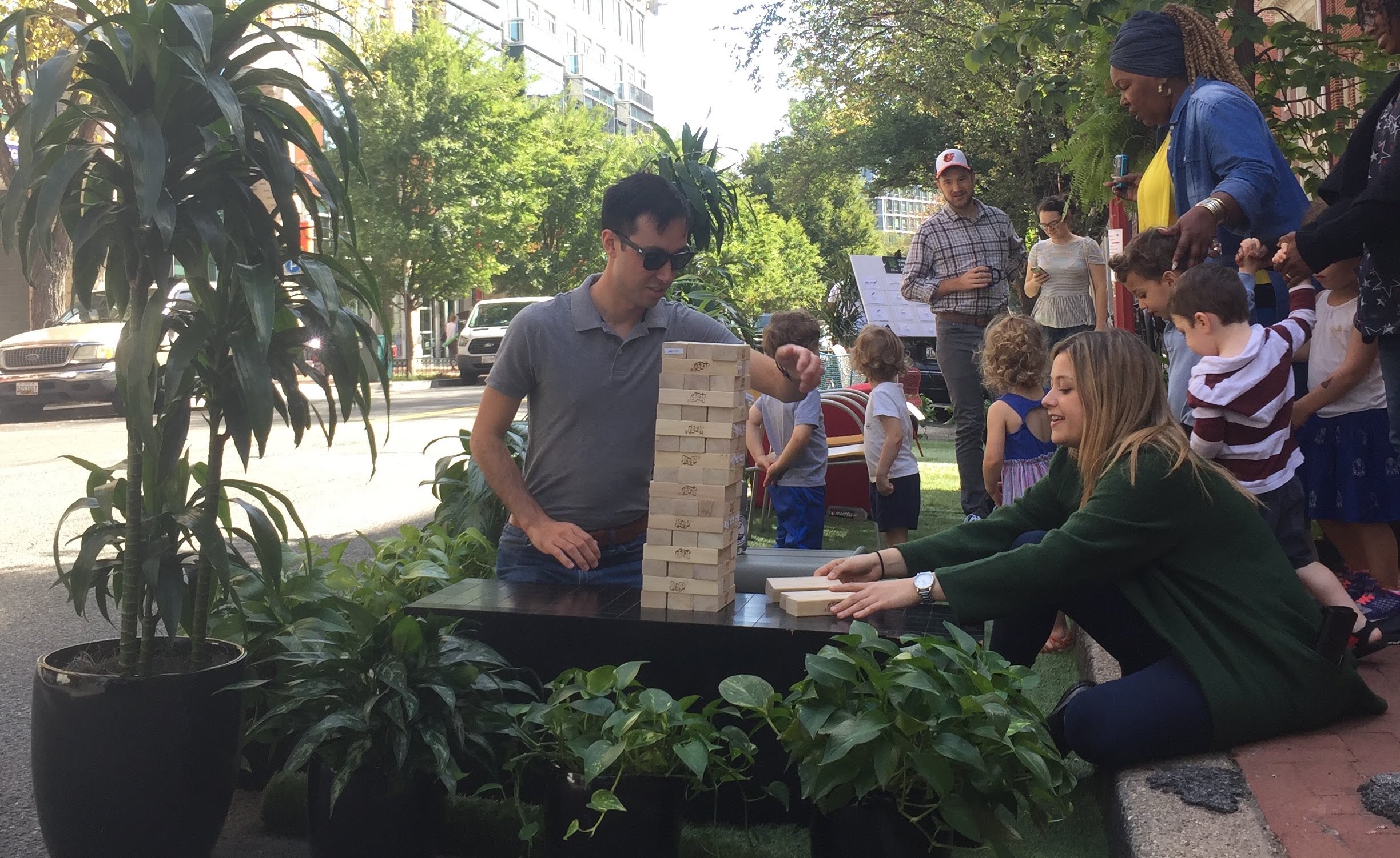  /></p>
<p>In 2005, three collaborators tested a new idea—they turned an underutilized and heavily subsidized piece of land (a parking spot) into a useful space with some grass, a bench, and a potted tree. People started using it almost immediately. Since posting the first picture of this DIY mini-park in San Francisco, this experiment in urban design has morphed into a global phenomenon. Now, hundreds of cities around the world hold PARK(ing) Day on the third Friday in September where dozens of parking spots that are usually reserved for stationary, empty cars are transformed into places for people.</p>
<p>According to John Bela, one of the brains behind the park that started it all, “it wasn’t necessarily about protest, but it was about demonstrating an alternative to storing cars in parking spaces.” It’s an important point. Cities—especially in North America—devote an insane amount of public space to storing empty, voluminous private vehicles. A recent study of parking shows that “car storage has become the primary land use in many city areas,” and at great expense.</p>
<p>Policies that require an excessive amount of parking for new development, based on unrealistic standards, can dramatically drive up the cost of housing or business space. And devoting 9-18 feet of street space for on-street parking takes up a lot of land that could otherwise be used for wider sidewalks, bike/scooter lanes, rain gardens, and—as PARK(ing) Day illustrates—many other public uses.</p>
<p>Below are a few of the “parklets” scattered around our office in Washington, DC and what their creators had to say about them.</p>
<h4><span>Island Press</span></h4>
<div class=