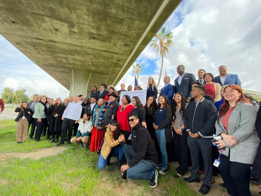 Community members gather beneath the 43rd Street exit, a large check in hand, ready to tackle their project